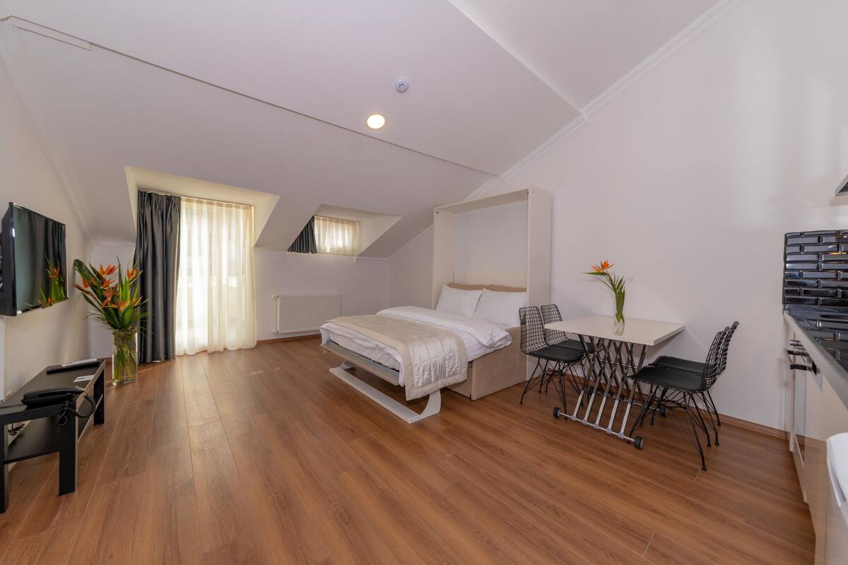 A modern, well-lit bedroom with a bed, a desk, and chairs.