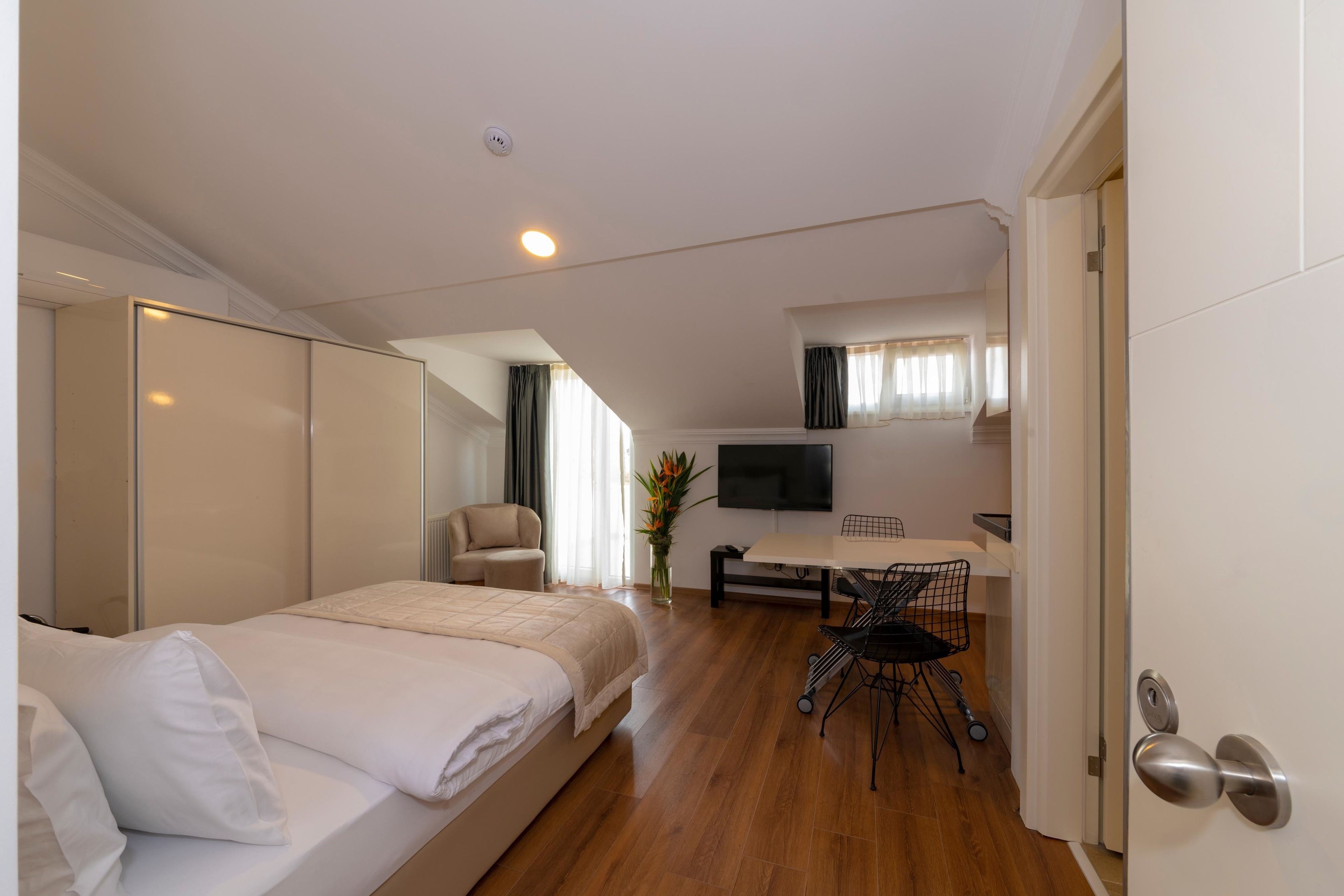 Une chambre d’hôtel moderne équipée d’un lit, d’un bureau, d’une chaise et d’un téléviseur.