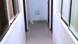 A narrow, tiled hallway with a door at the end, flanked by windows with blinds. - Casa Blanca Machu Picchu B&B (Machu Picchu)