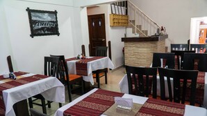 A dining area with tables set for two, chairs, and a staircase in the background. - Casa Blanca Machu Picchu B&B (Machu Picchu)
