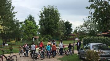 A group of people with bicycles in a park with trees and a playground.