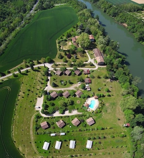 Vue aérienne d’un quartier résidentiel avec des maisons, une piscine et une rivière.