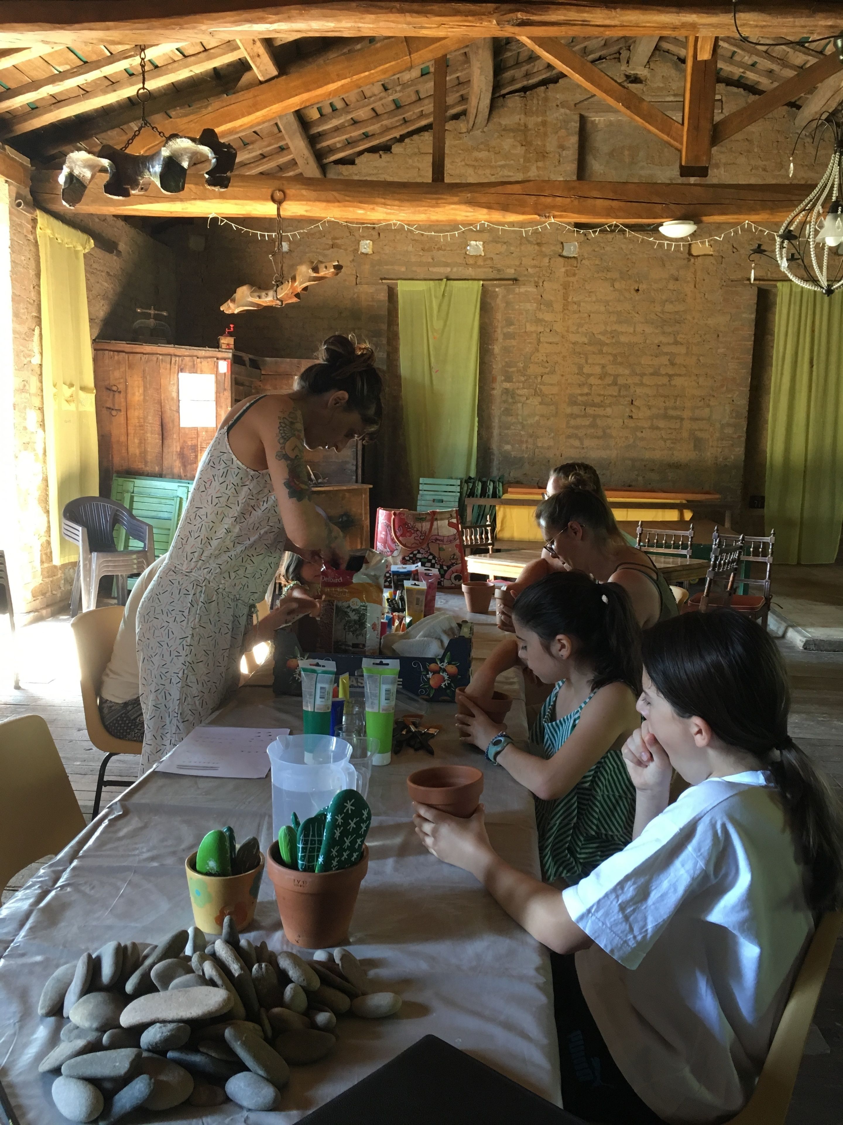 A rustic room with exposed wooden beams, a brick wall, and a table with people engaged in an activity.