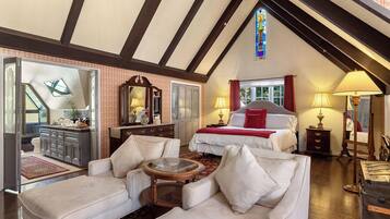 A spacious room with a large bed, a sitting area with a coffee table, and a view of the outdoors through a window.