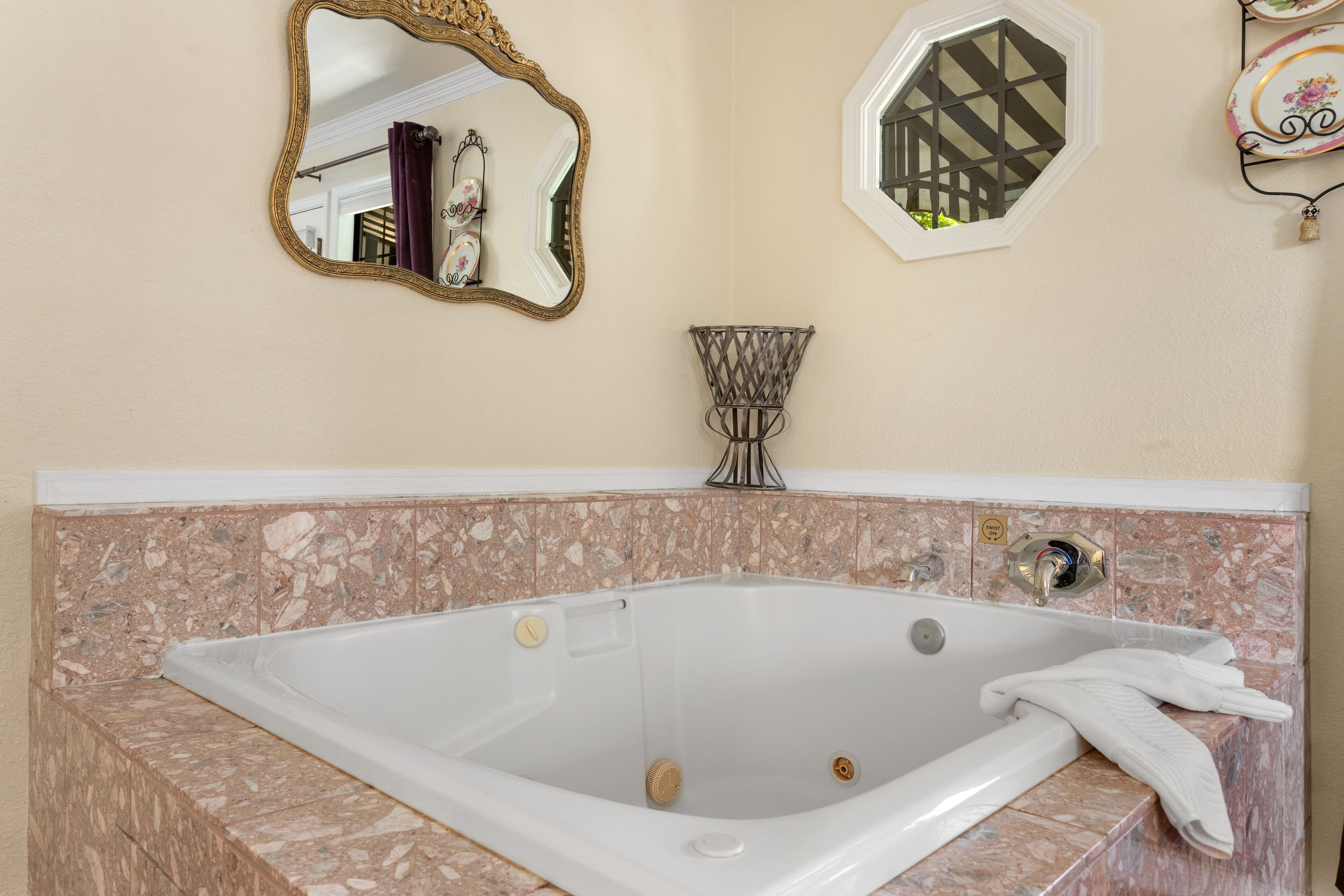 A bathroom with a freestanding bathtub, a large mirror, and a decorative wall piece.