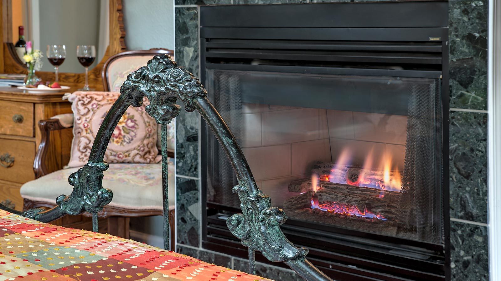 A fireplace with a modern design, a decorative metal armrest, and a patterned tablecloth.