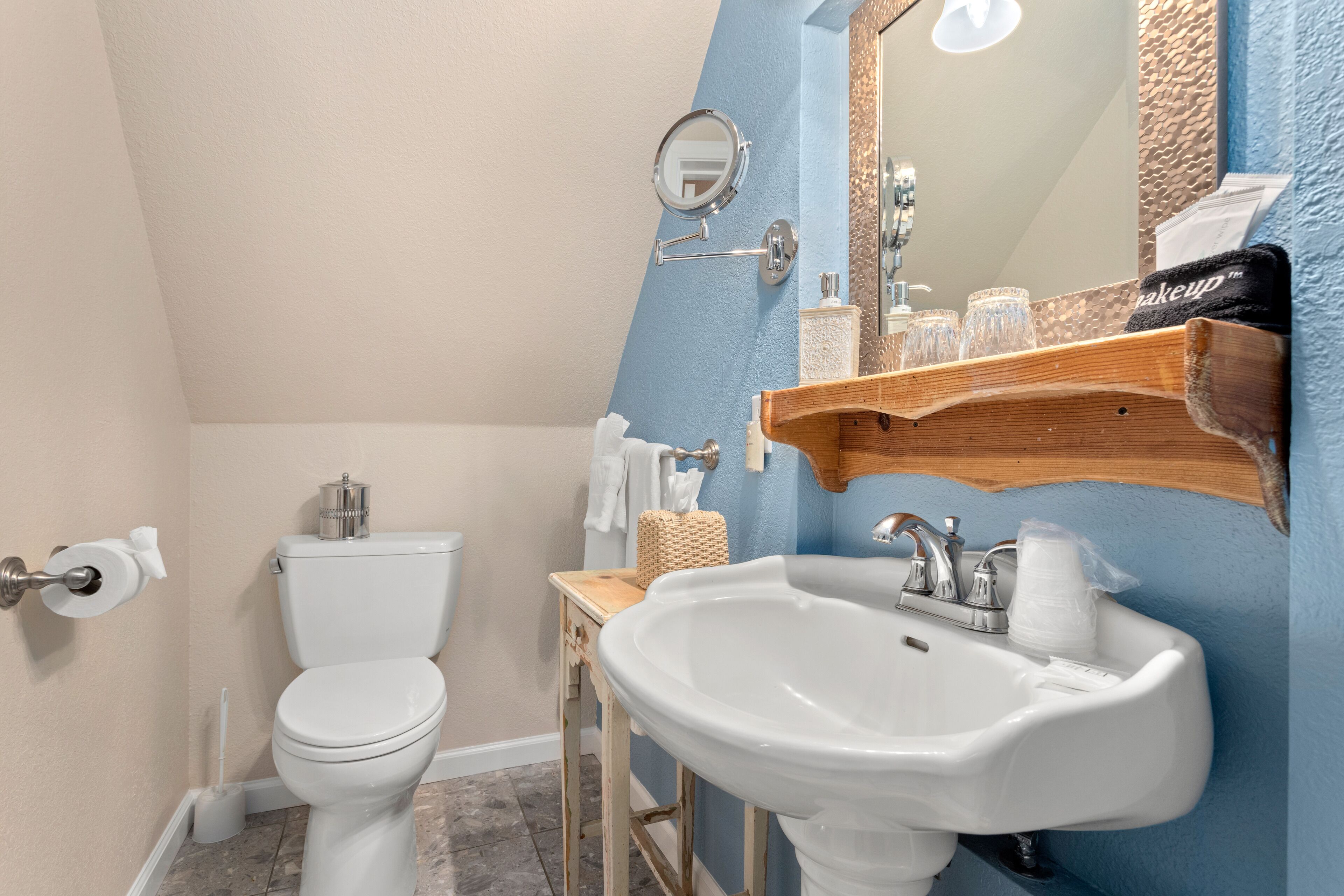 Une salle de bain avec des toilettes blanches, un lavabo et un miroir.