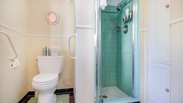 Une salle de bain comprenant des toilettes, une douche avec une porte en verre et un lavabo.