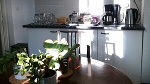 Une cuisine avec des meubles blancs, une table en bois et des plantes en pot.