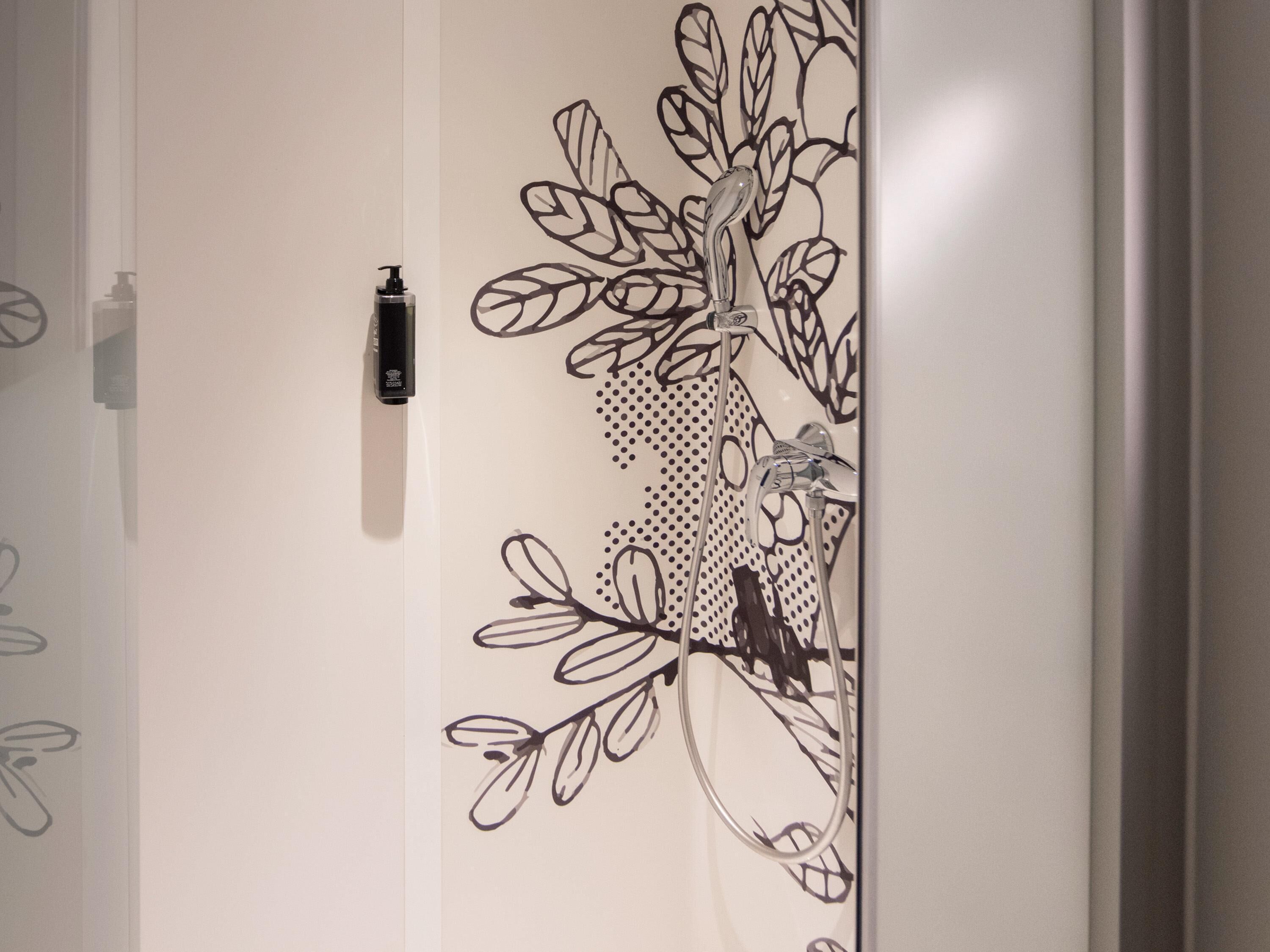 Un muro con un disegno floreale nero e un erogatore di gel disinfettante.