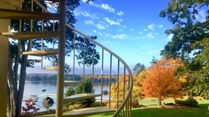 Un escalier en colimaçon mène à une terrasse d’où l’on peut admirer un lac et les couleurs automnales des arbres.