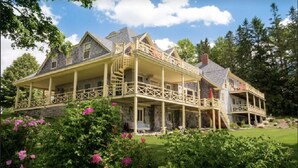 Une grande maison à deux étages, dotée d’un balcon et d’un porche abrité.