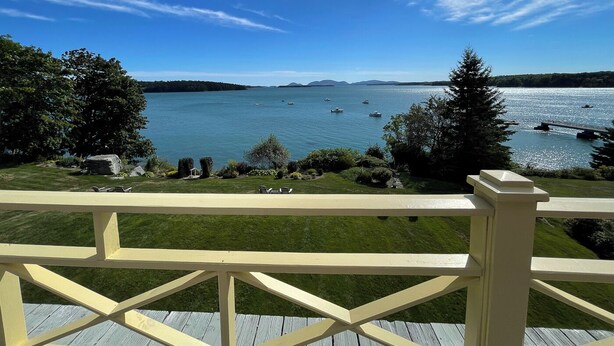A deck with a view of a lake, boats, and distant land.