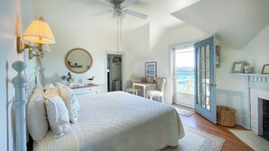 Une chambre à coucher comprenant un lit, un bureau, une chaise, une cheminée et une vue sur l’extérieur.
