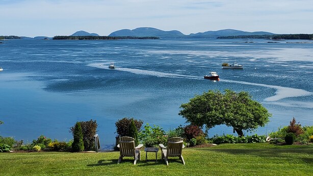 Une vue sur le lac, avec des bateaux, des chaises et une zone herbeuse.