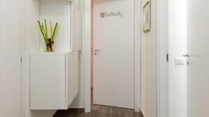 Un couloir aux murs blancs, une porte portant l’inscription « Papillon » et une petite plante posée sur un meuble.