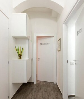 Un couloir aux murs blancs, une porte portant l’inscription « Papillon » et une petite plante posée sur un meuble.