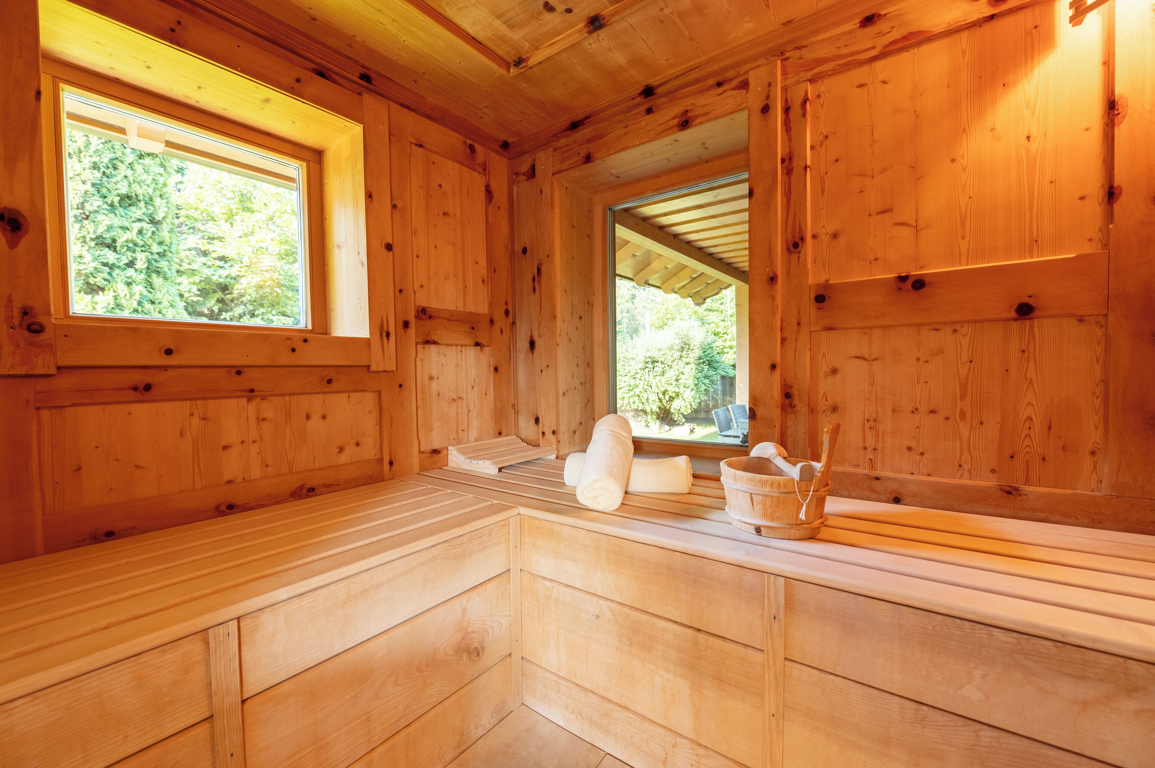 Ein Holzblockbau-Innenraum mit einer Bank, einem Fenster und einer Holzbalkendecke.