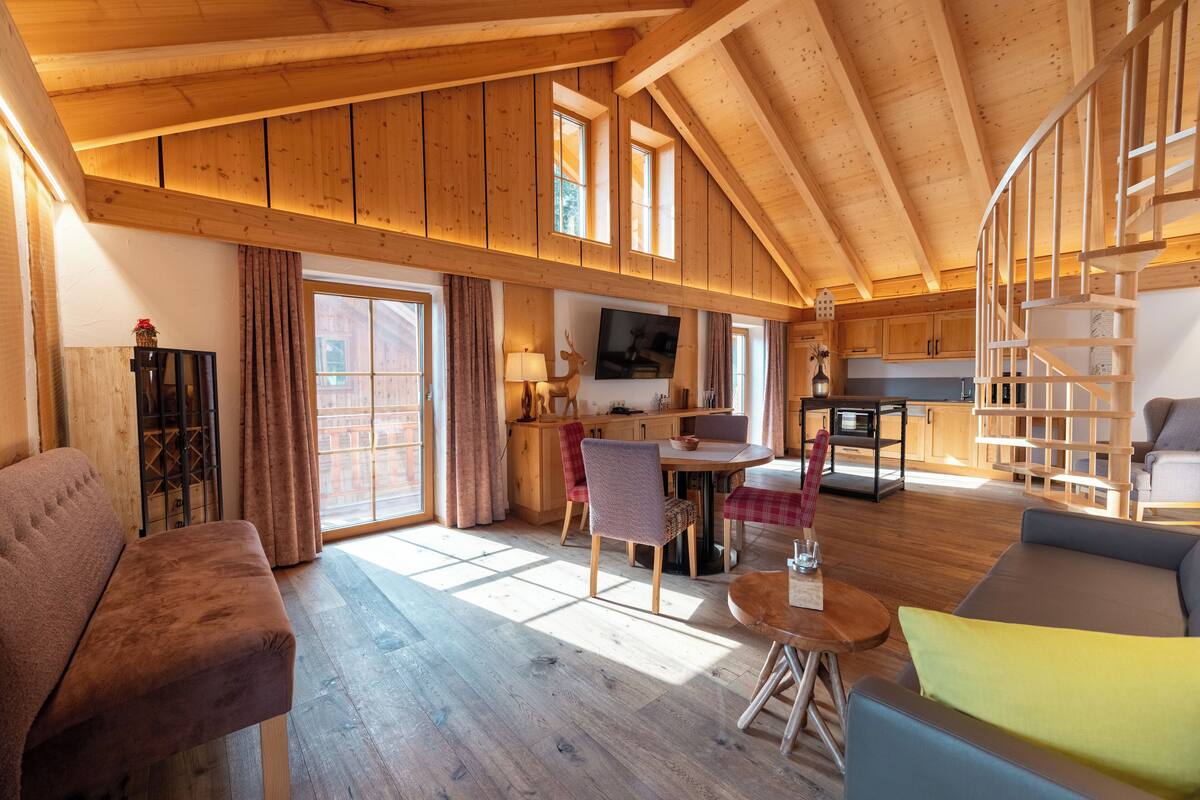 A spacious living area with a wooden ceiling, a dining table, and a sofa.