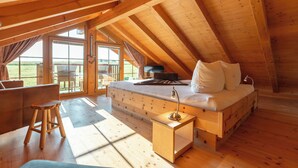 Een gezellig slaapkamer onder het dak met een houten bed, een klein krukje en een nachtkastje.