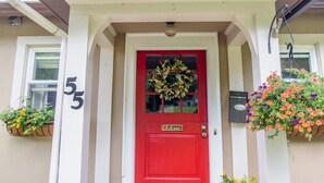 A red door with a wreath, number 5, and flower baskets on either side. - The Red Door B&B (Lee)