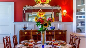A dining table set with placemats, candles, and a centerpiece of flowers. - The Red Door B&B (Lee)