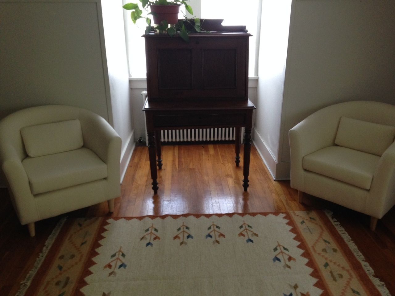 A living room with two armchairs, a wooden coffee table, and a patterned rug.