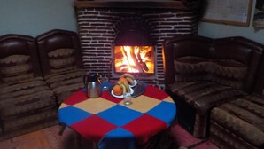 Una habitación acogedora con chimenea de ladrillo, sillones de cuero y una mesa con mantel a cuadros.