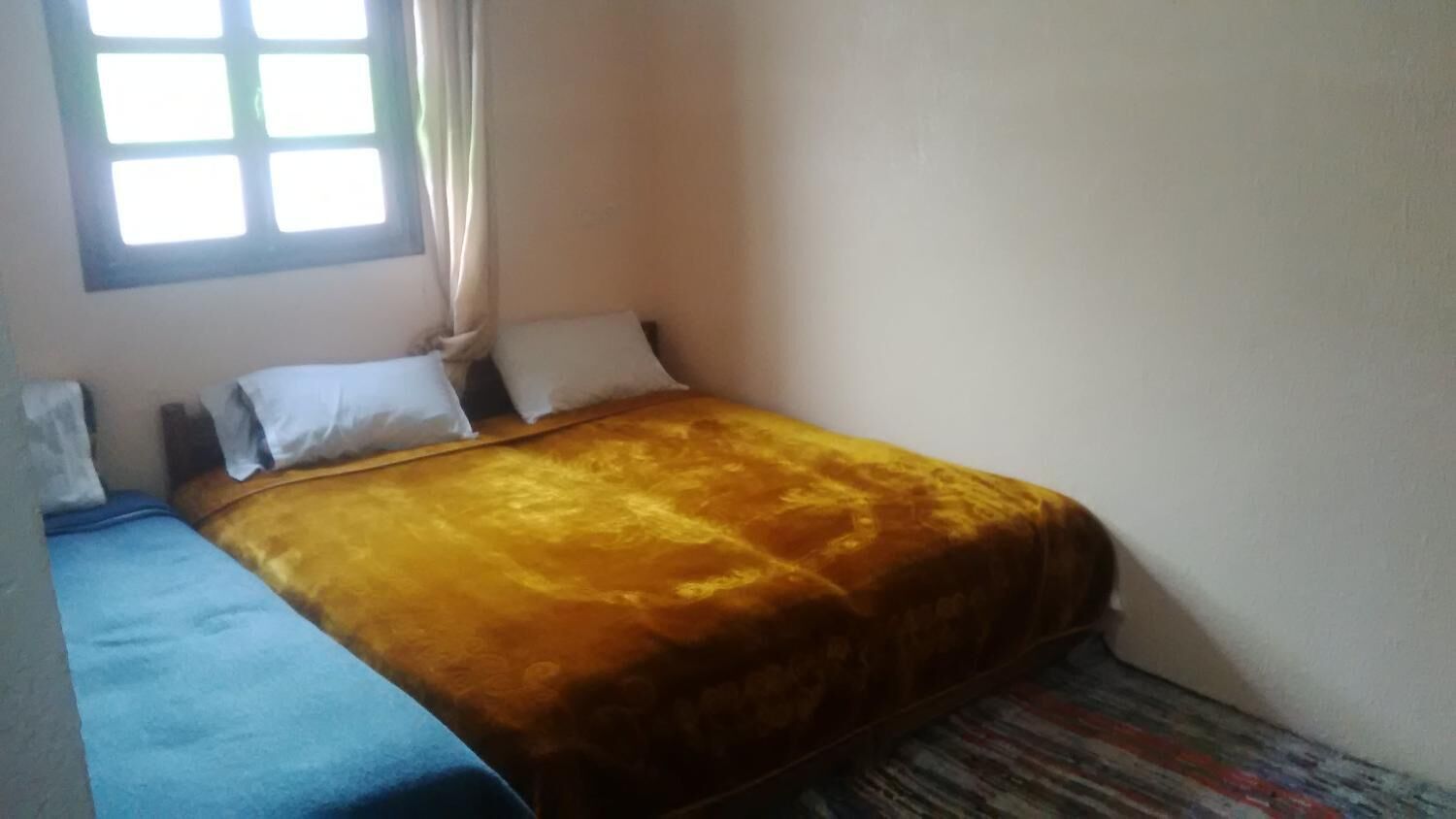 Un dormitorio con cama, ventana y cortina.