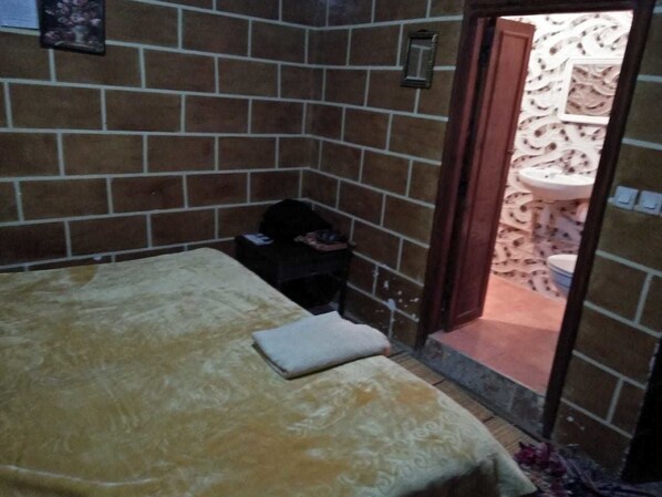 Une petite pièce comprenant un lit, une petite table et une porte donnant sur une salle de bain.
