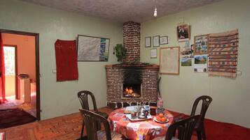 A dining area with a brick fireplace, a table set for two, and various wall decorations.