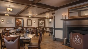 A restaurant with wooden floors, tables set for dining, and a fireplace. - Rabbit Hill Inn (Lower Waterford)