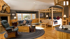 A log cabin-style room with a large bed, a rocking chair, a fireplace, and a wooden ceiling. - Rabbit Hill Inn (Lower Waterford)