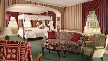 Een slaapkamer met een hemelbed, een bank, een stoel en een salontafel.