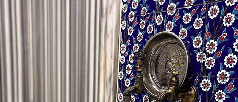 A bathroom with a marble sink, a faucet, and a wall with floral tile design.