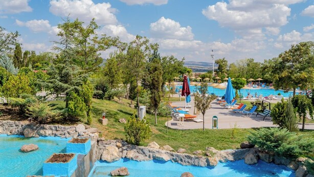 A pool area with multiple swimming pools, lounge chairs, and umbrellas.
