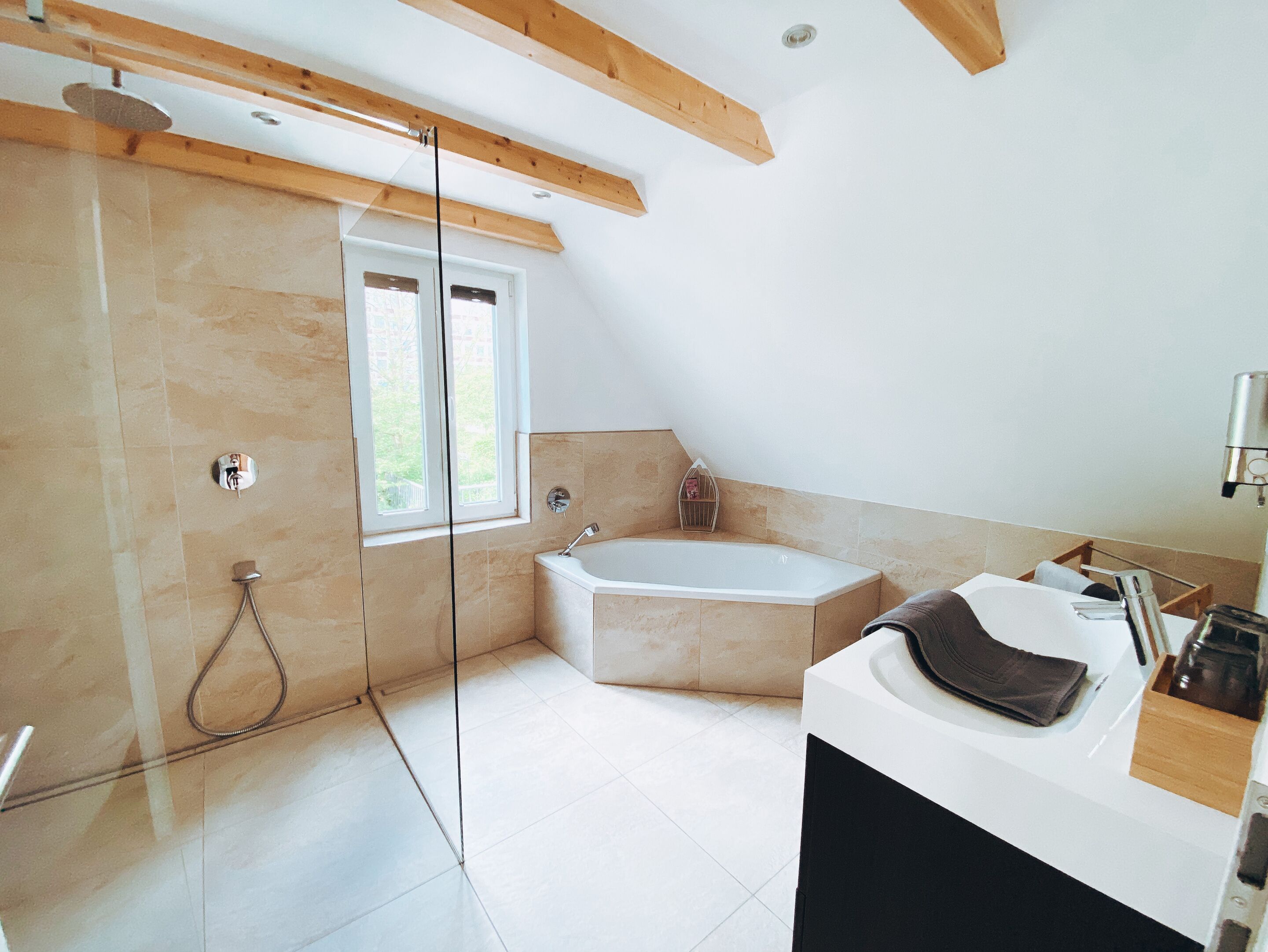 Une salle de bain moderne avec une baignoire, une douche et une fenêtre.