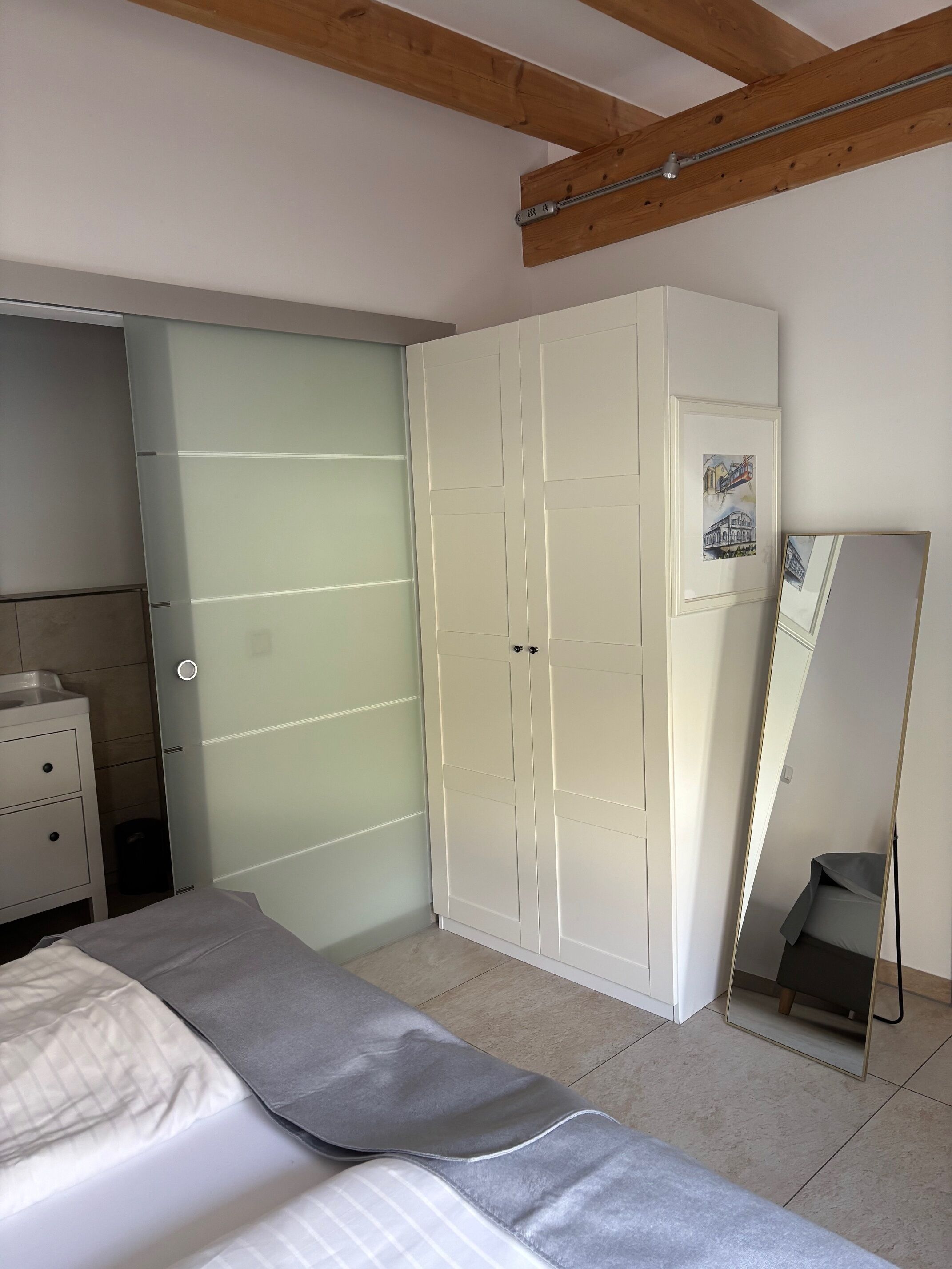 Un dormitorio con cama, armario, espejo y una mesita de noche.