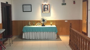 A room with a table covered by a teal cloth, a fan, and a framed picture on the wall. - Hostal Castilla (Torrenueva)