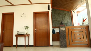 Una habitación con dos puertas de madera, una mesa pequeña con un jarrón y una pared de piedra.