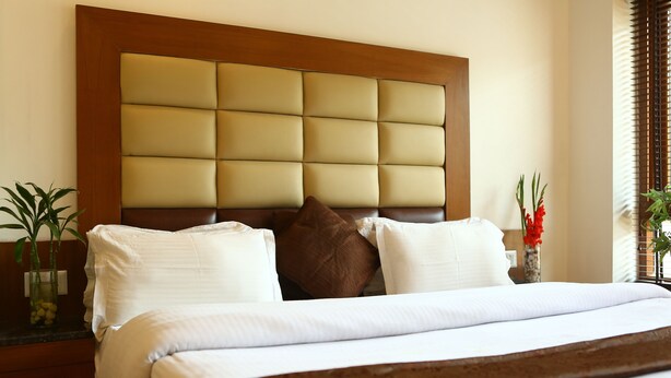 Una cama bien hecha con cabecera de madera y ropa de cama blanca.