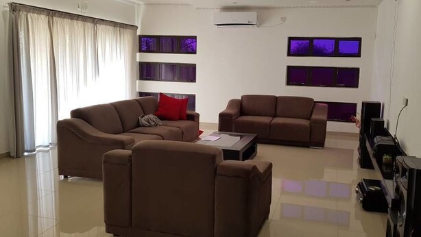 A modern living room with two brown sofas, a coffee table, and a flat-screen TV. - Styled Bed and Breakfast (Palapye)