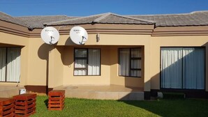 A two-story building with satellite dishes, a flat roof, and a small lawn area. - Styled Bed and Breakfast (Palapye)