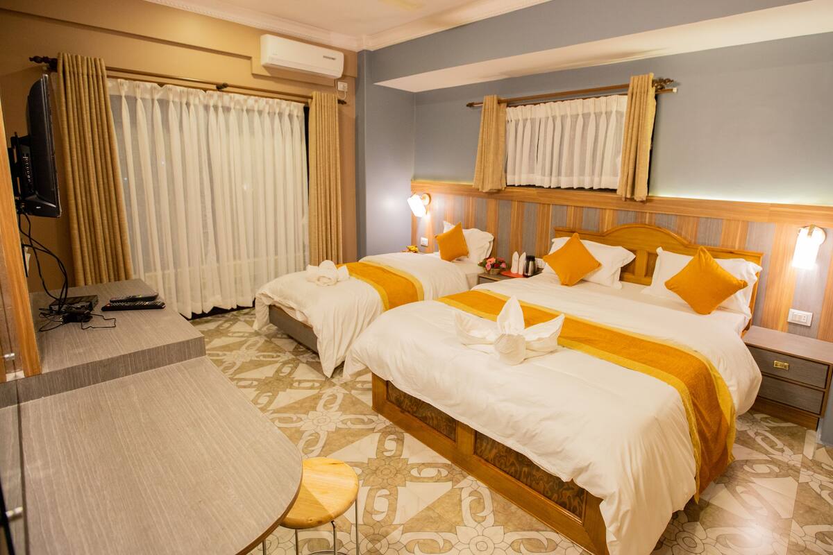 Une chambre d’hôtel avec deux lits, une télévision, un bureau et un sol à motifs.