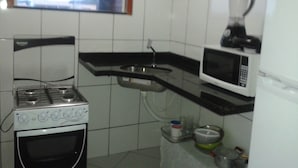 A compact kitchen with a gas stove, microwave, and a small refrigerator. - Buzios Apartamentos (Búzios)