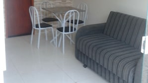 A living room with a sofa, a dining table with chairs, and a door. - Buzios Apartamentos (Búzios)