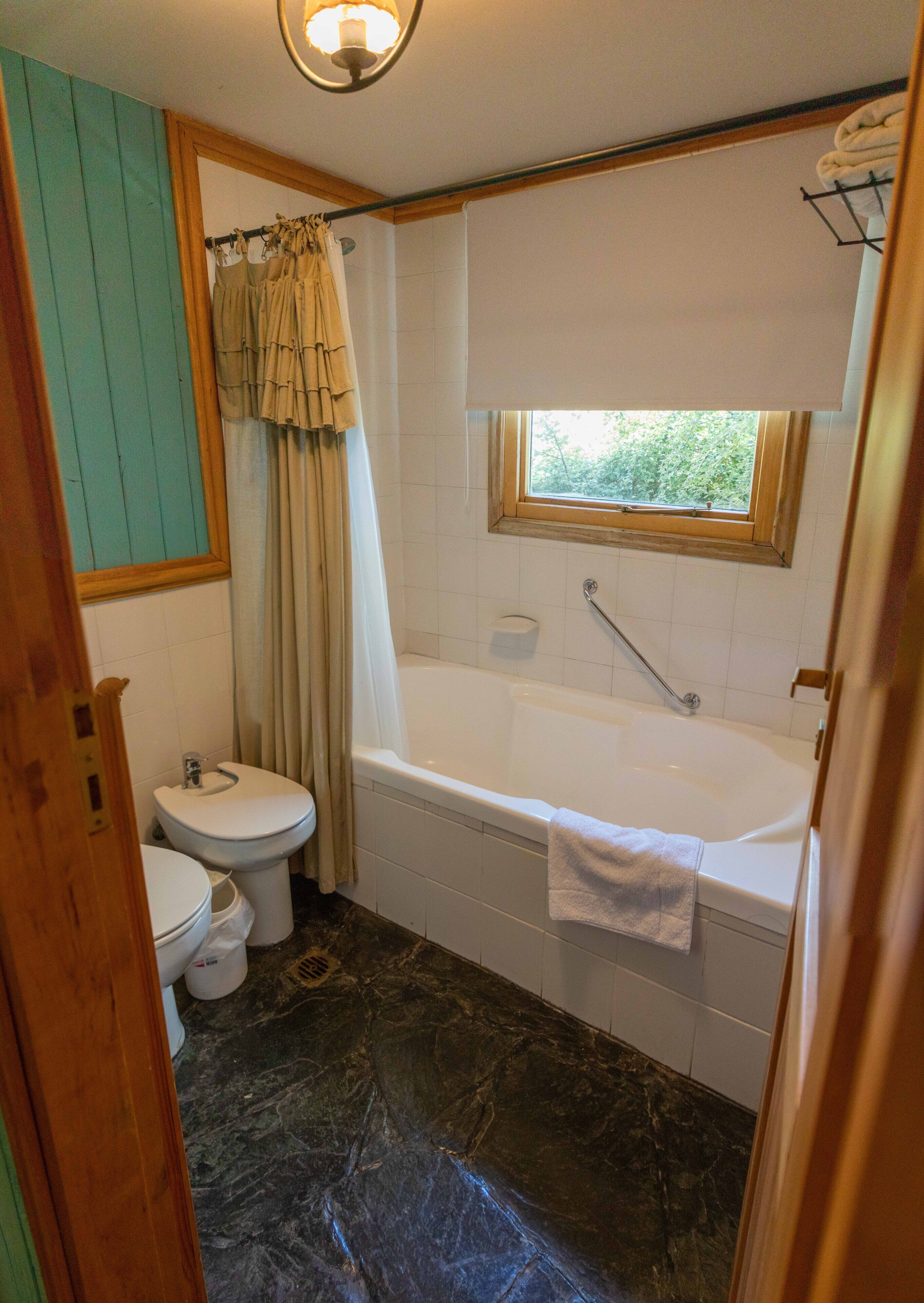 Un baño con inodoro, bañera y ventana.