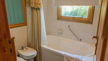 Un baño con inodoro, bañera y ventana.