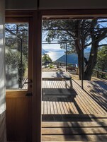 A wooden deck with a bench and a table, overlooking a scenic landscape with mountains and a body of water.