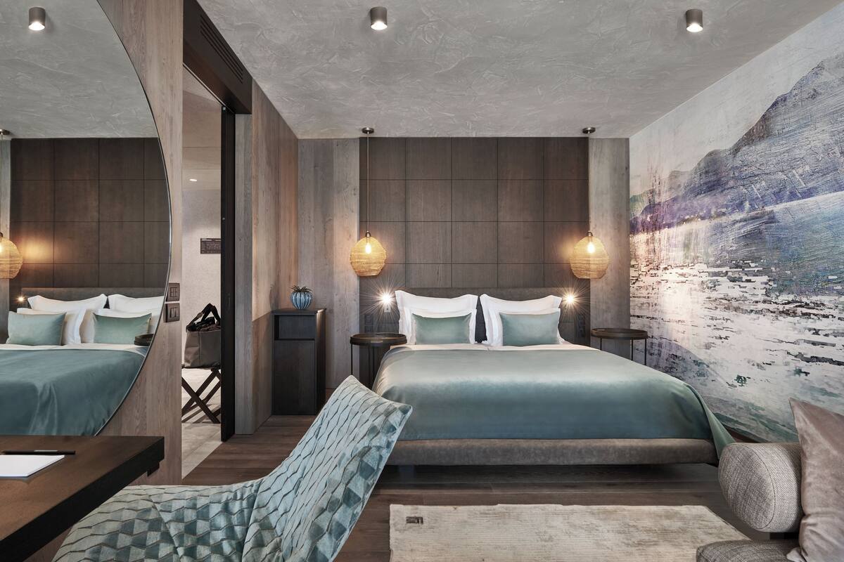 Un dormitorio moderno con dos camas, paneles de madera y un gran mural de un paisaje montañoso.